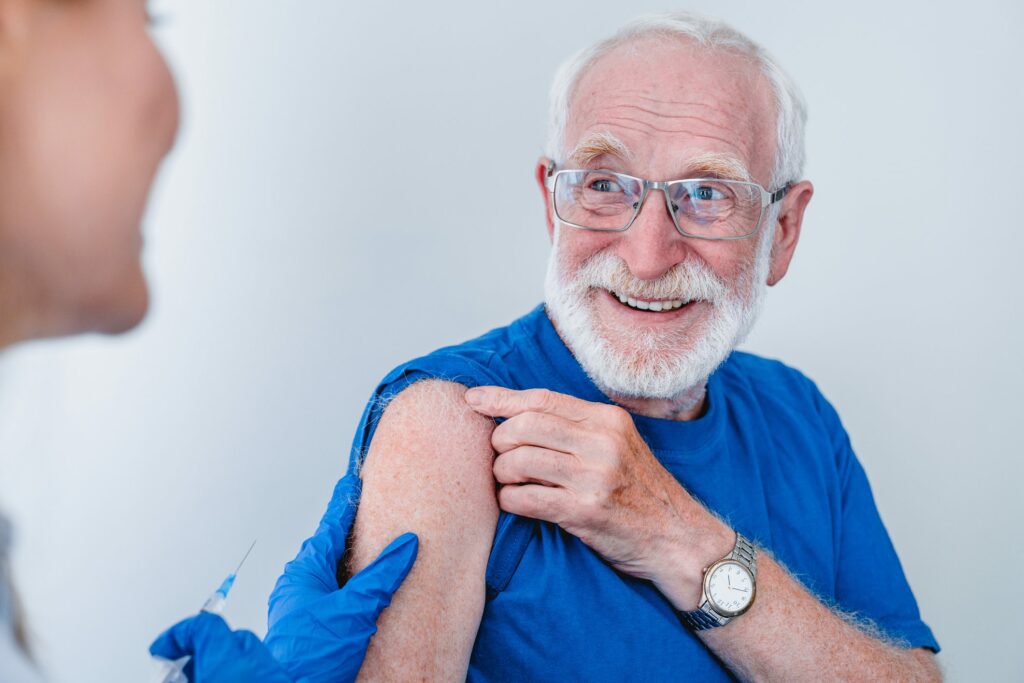 Smiling elderly patient in glasses is getting ready for injection