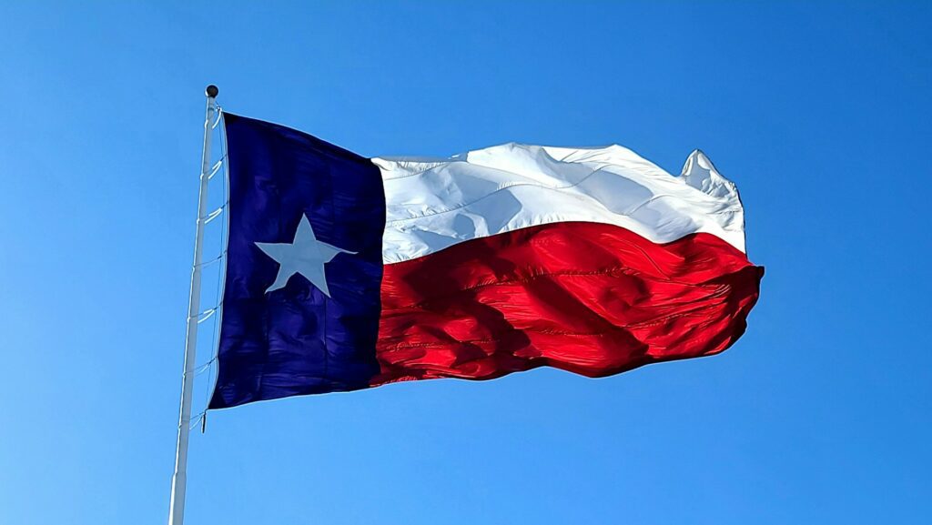 texas flag waving against blue sky